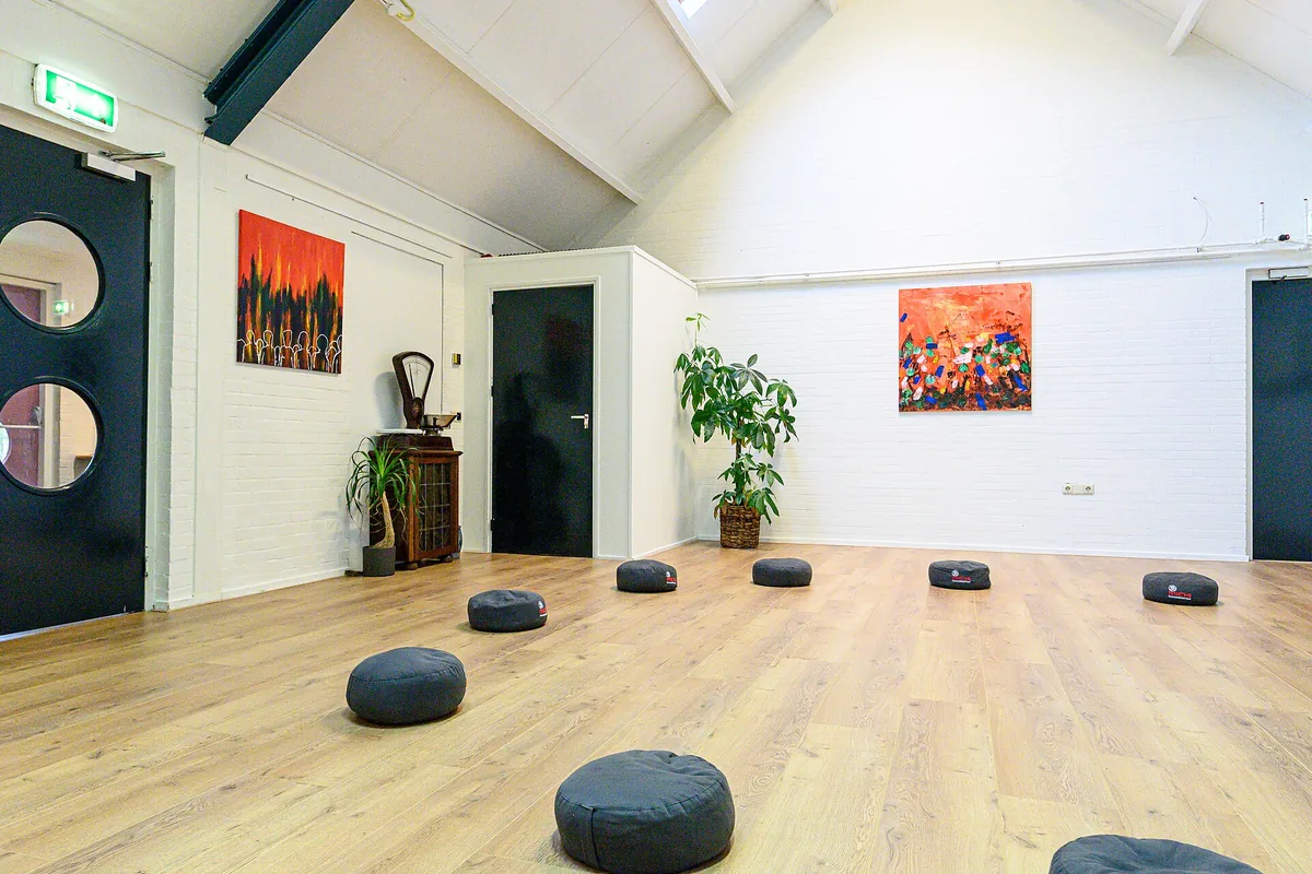 An empty bright studio room with round meditation cushions on a wooden floor
